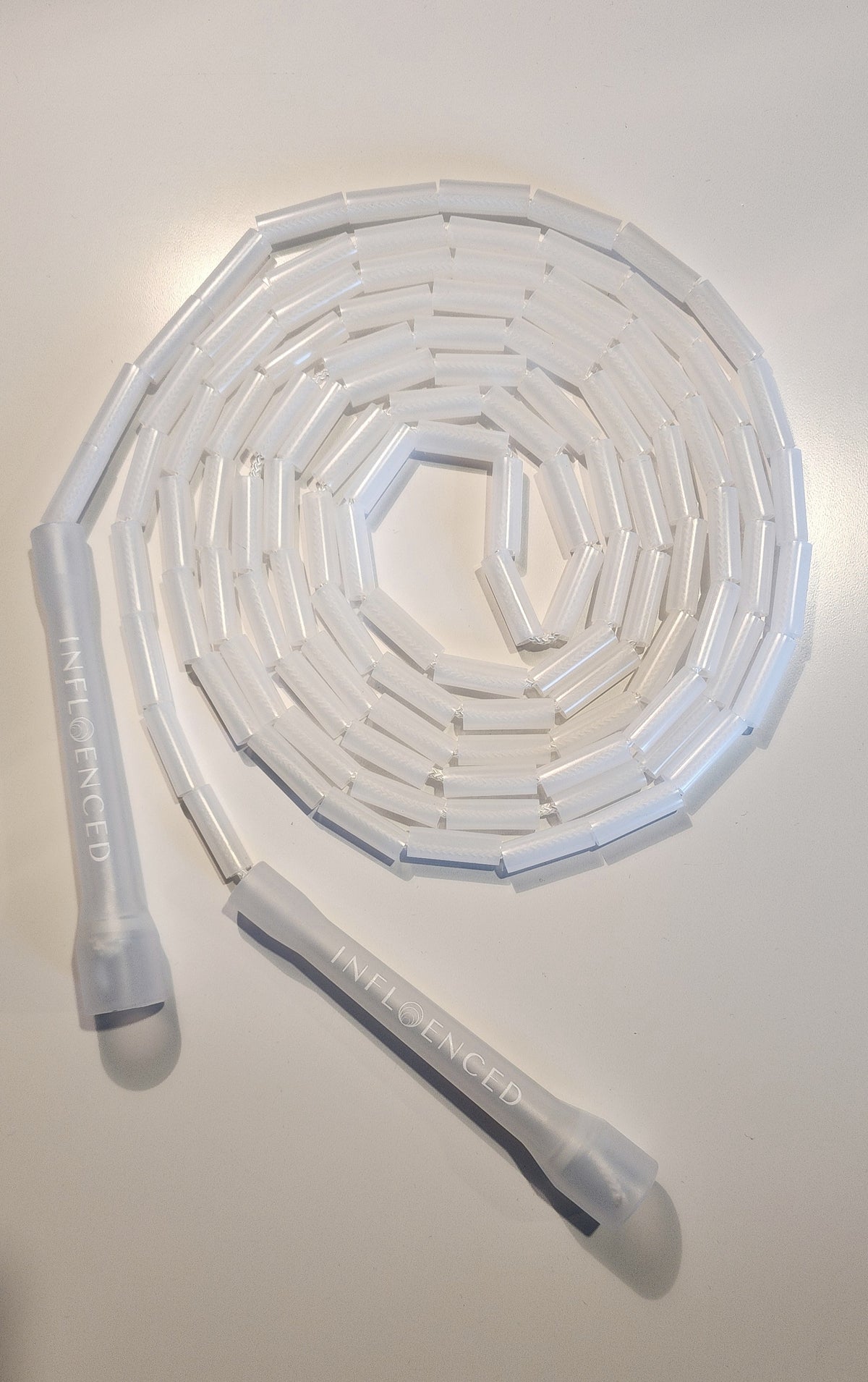 A transparent jump rope or cord arranged in a spiral shape on a light background
