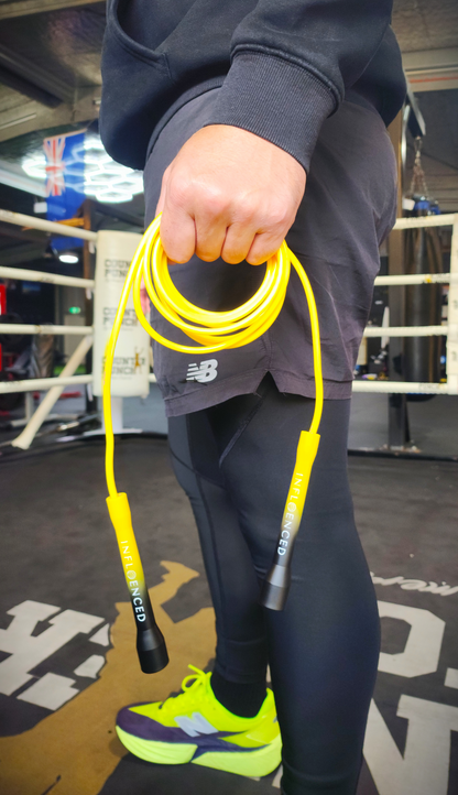A person in a boxing gym holding a yellow and black PVC Jump rope by Infloenced