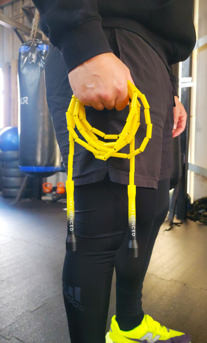 A person in a boxing gym holding a yellow and black beaded jumprope by Infloenced
