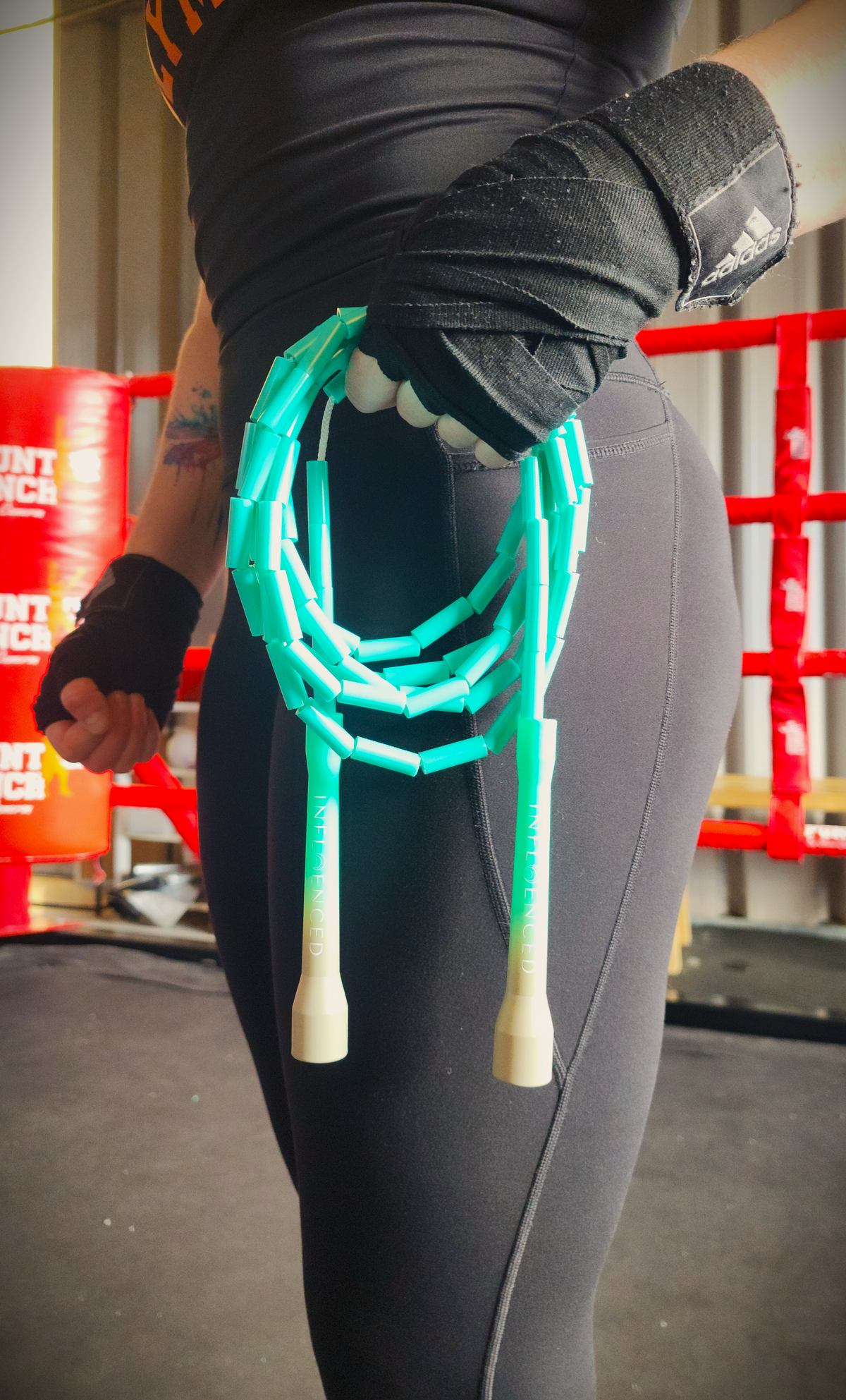 A person in a boxing gym holding a teal green and grey beaded jump rope by Infloenced