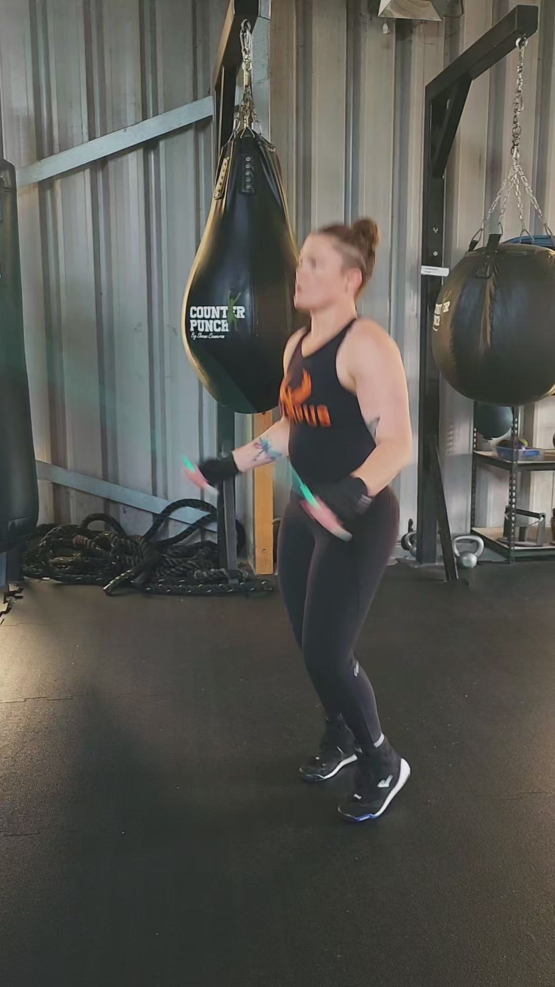 a girl skipping in a boxing gym practicing speed and footwork with a teal green and grey pvc jump rope