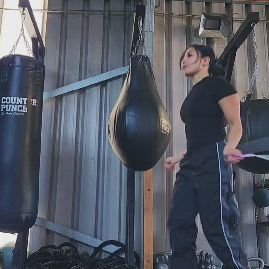 a girl skipping in a boxing gym practicing releases and coordination with a white and pink beaded jump rope