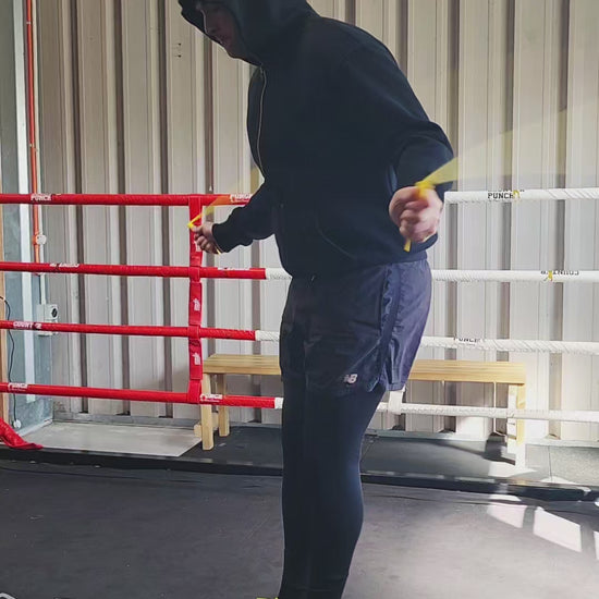 a person skipping in a boxing gym practicing speedwork with a black and yellow pvc jump rope