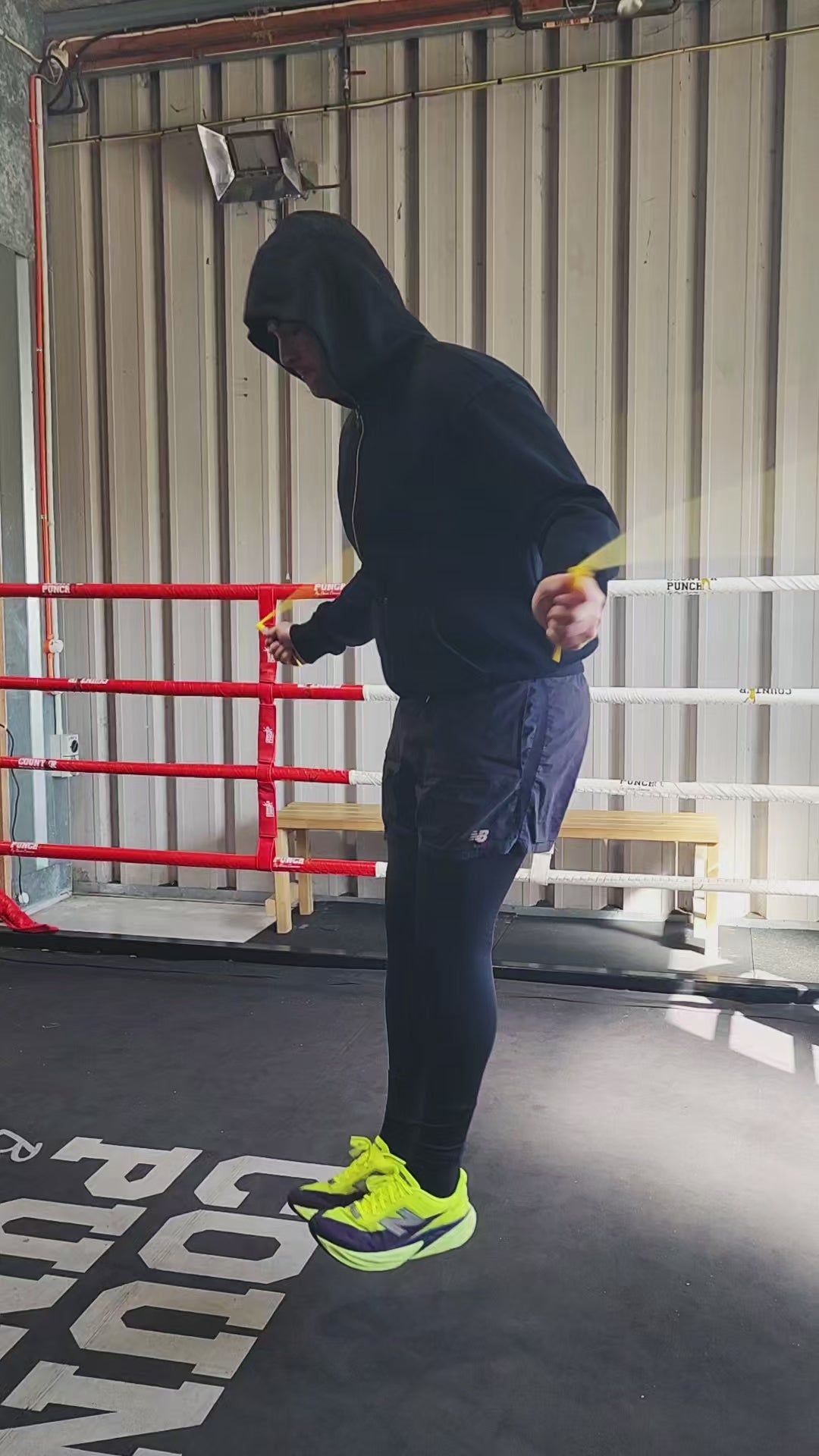 a person skipping in a boxing gym practicing speedwork with a black and yellow pvc jump rope