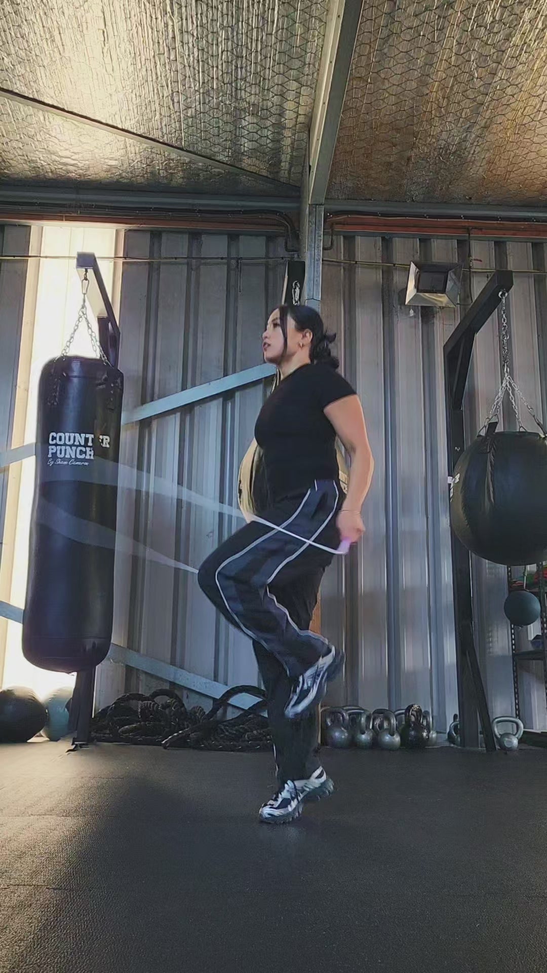 a girl skipping in a boxing gym practicing footwork with a white and pink pvc jump rope