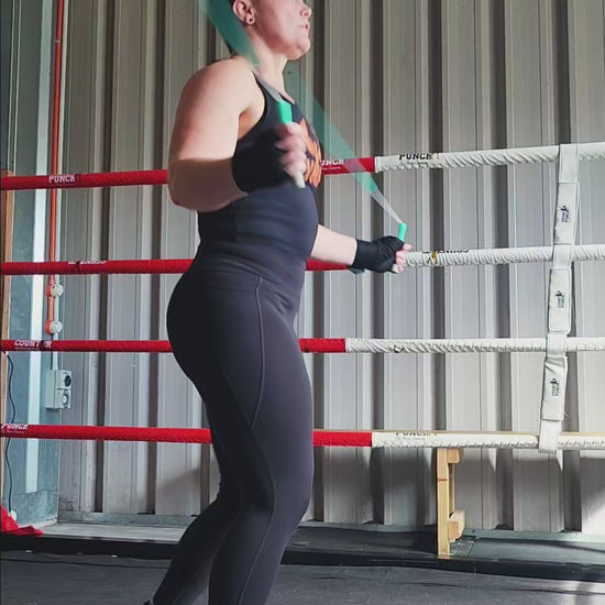 a girl skipping in a boxing gym practicing footwork and coordination with a teal green and grey beaded jump rope