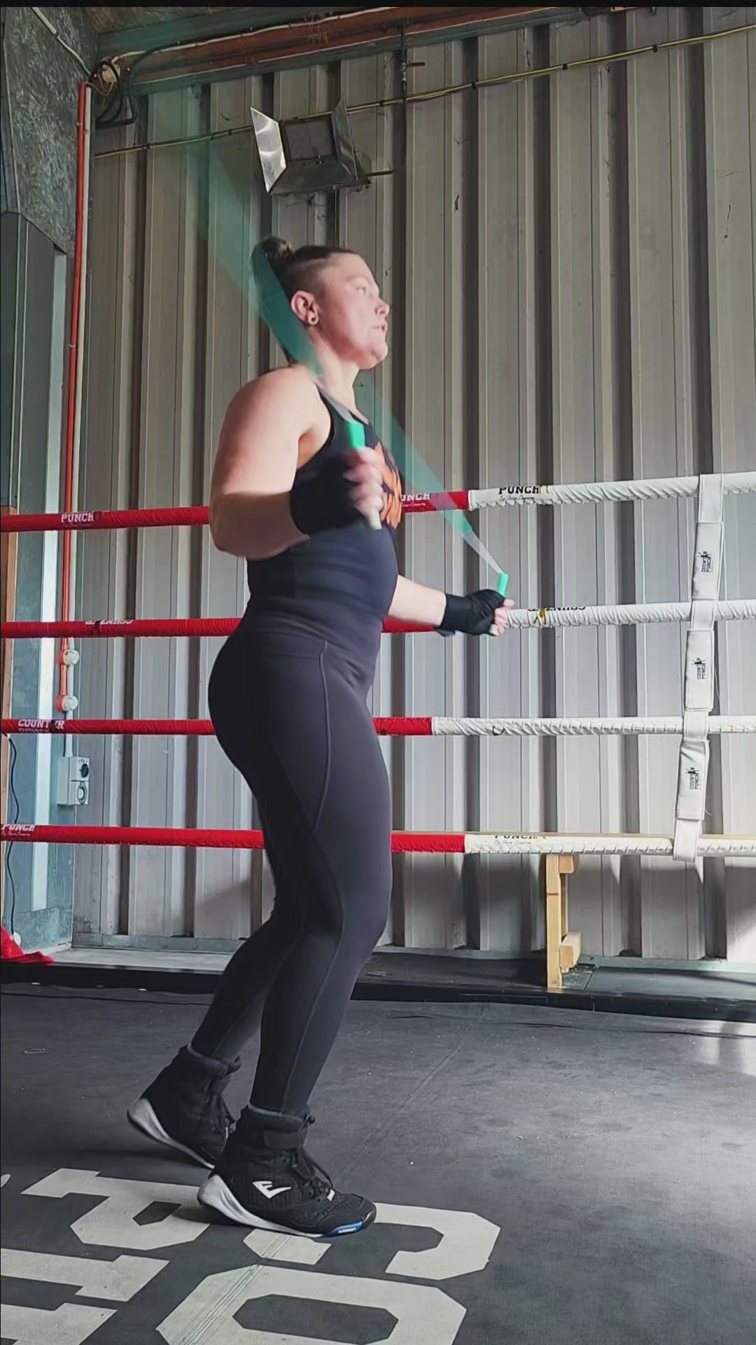 a girl skipping in a boxing gym practicing footwork and coordination with a teal green and grey beaded jump rope