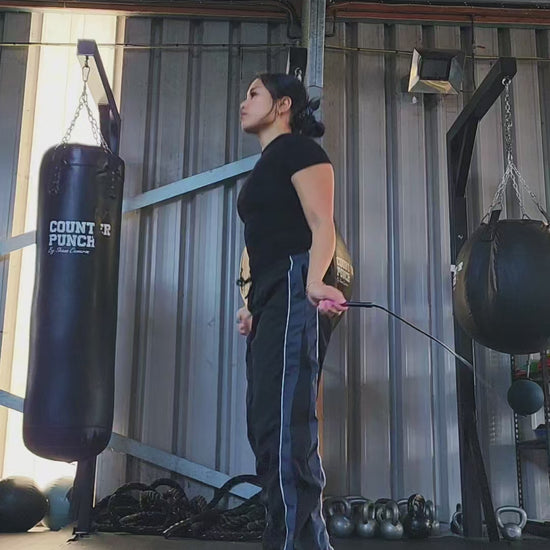 a girl skipping in a boxing gym practicing footwork with a black and pink pvc jump rope