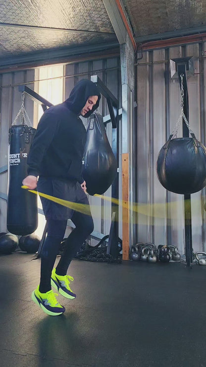 a person skipping in a boxing gym practicing rhythm and coordination with a yellow and black beaded jump rope